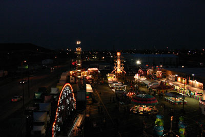 View from the top of the Ferris wheel. Out in the distance, past the flash and glitter of the midway, lie the lights of the refineries that built southwest Tulsa; at left, cars approach on historic Route 66.